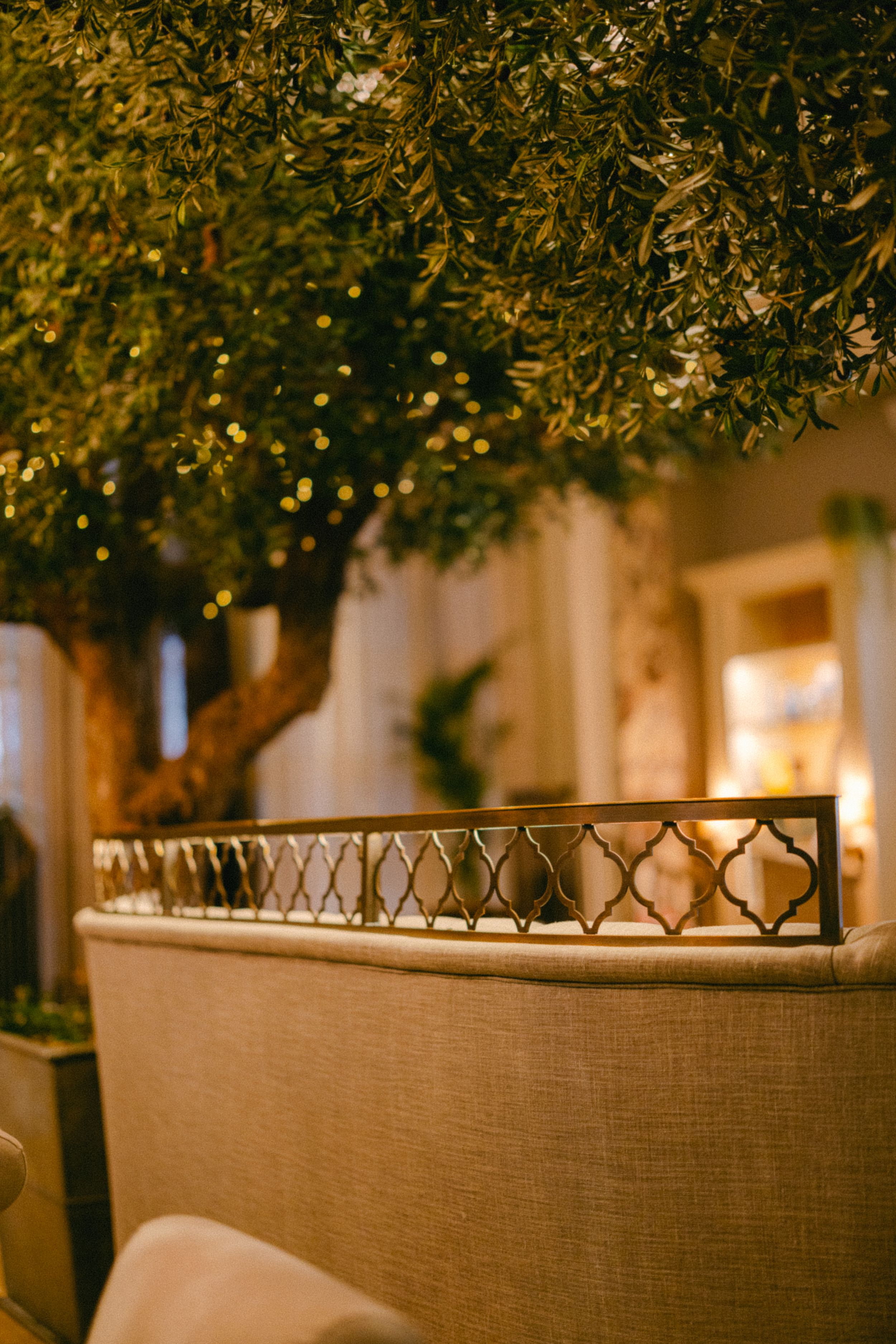 Elegant restaurant interior with illuminated tree and beige upholstered seating.
