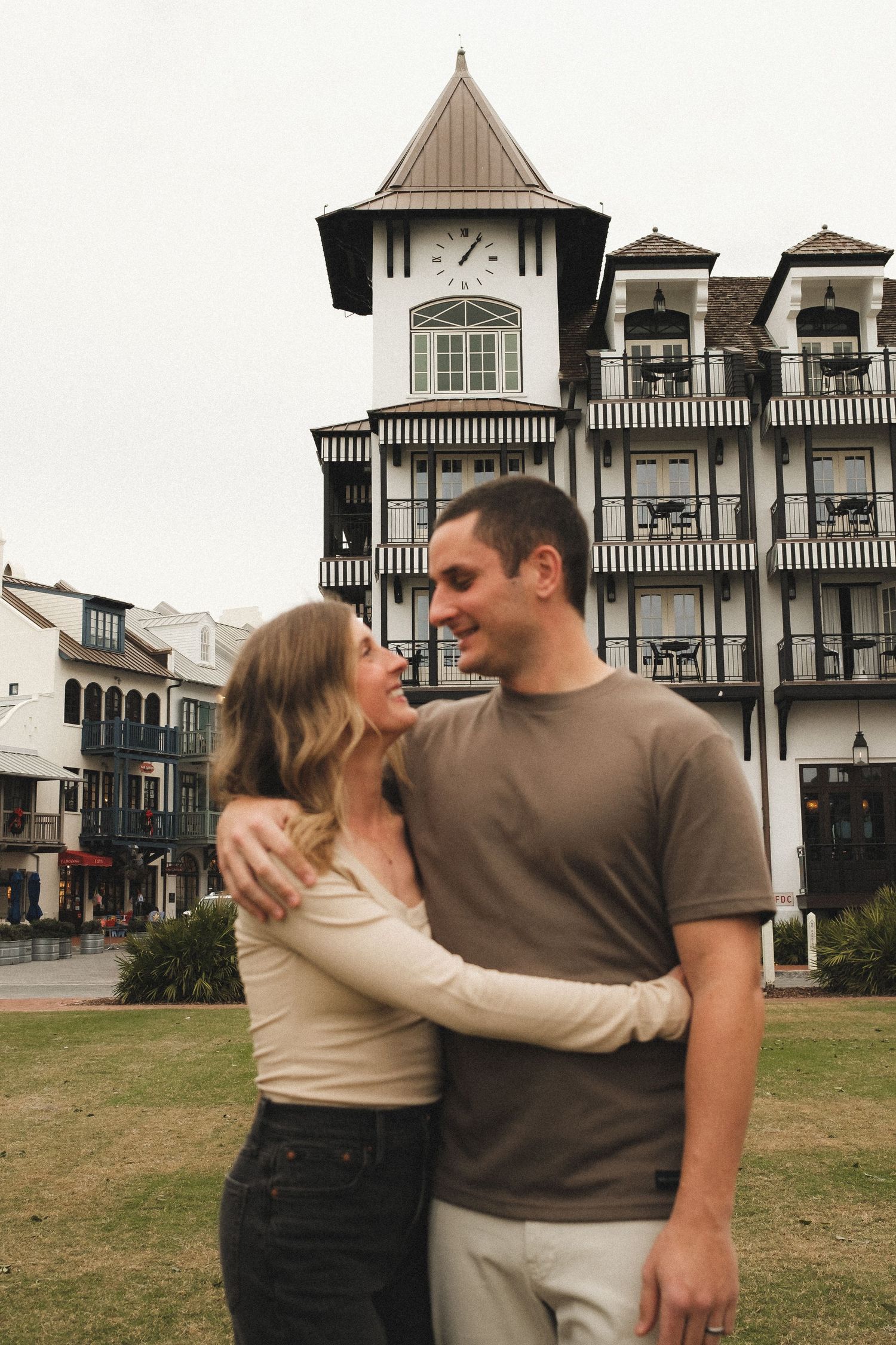 Couple walking and embracing near Victorian-style buildings with distinctive architecture.