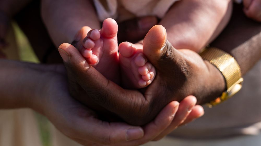 Tiny baby feet rest gently in caring hands.