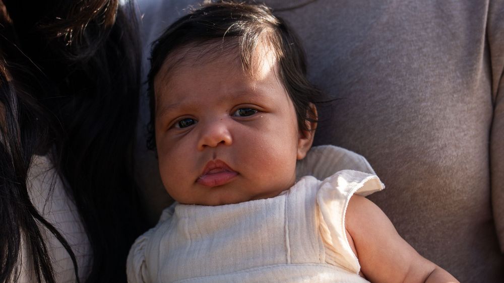 Close up portrait of an infant wearing white against a soft background.