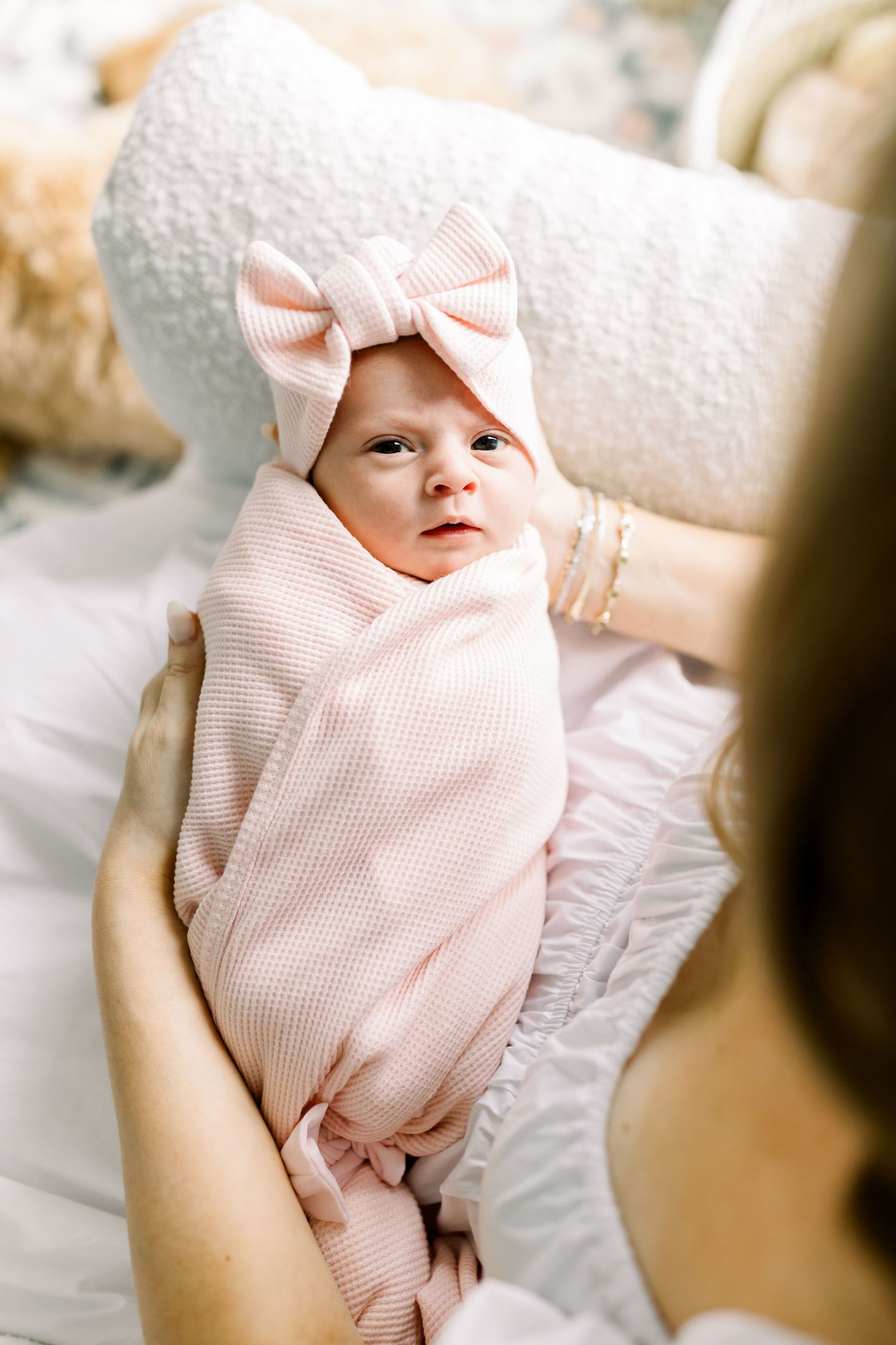 Baby wearing pink bow headband and swaddle wrap.