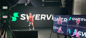 An instructor from Swerve fitness premium cycling workouts live streaming fitness to gyms around the world in front of the 20'x8' LED wall