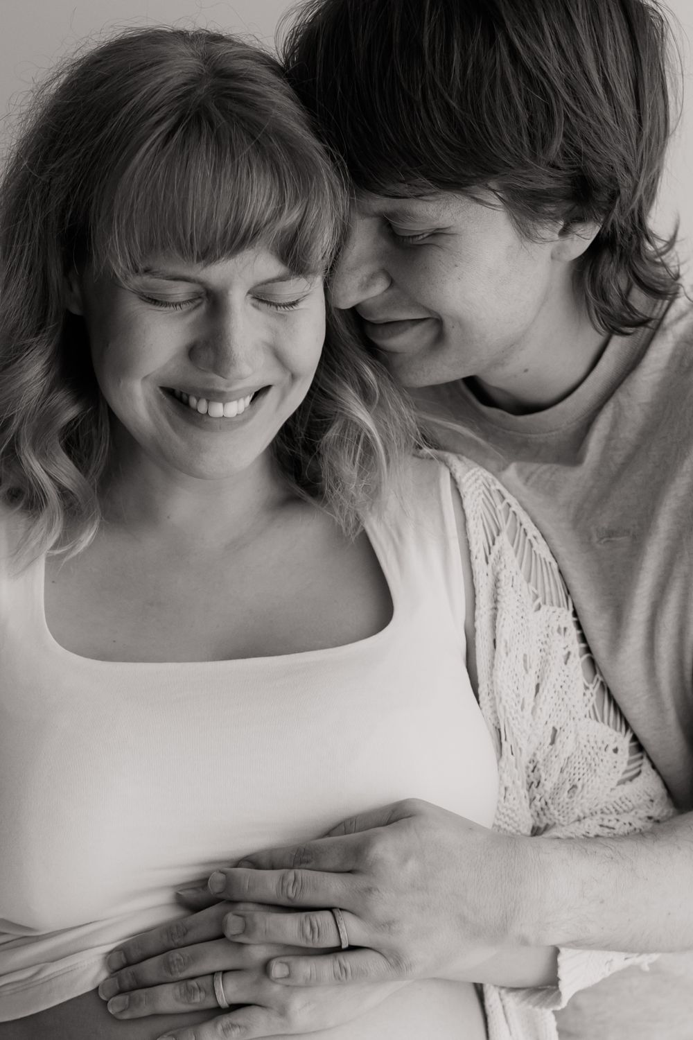 Odotuskuvaus studiossa Turussa. A tender black and white portrait of a couple sharing an intimate moment together while smiling.