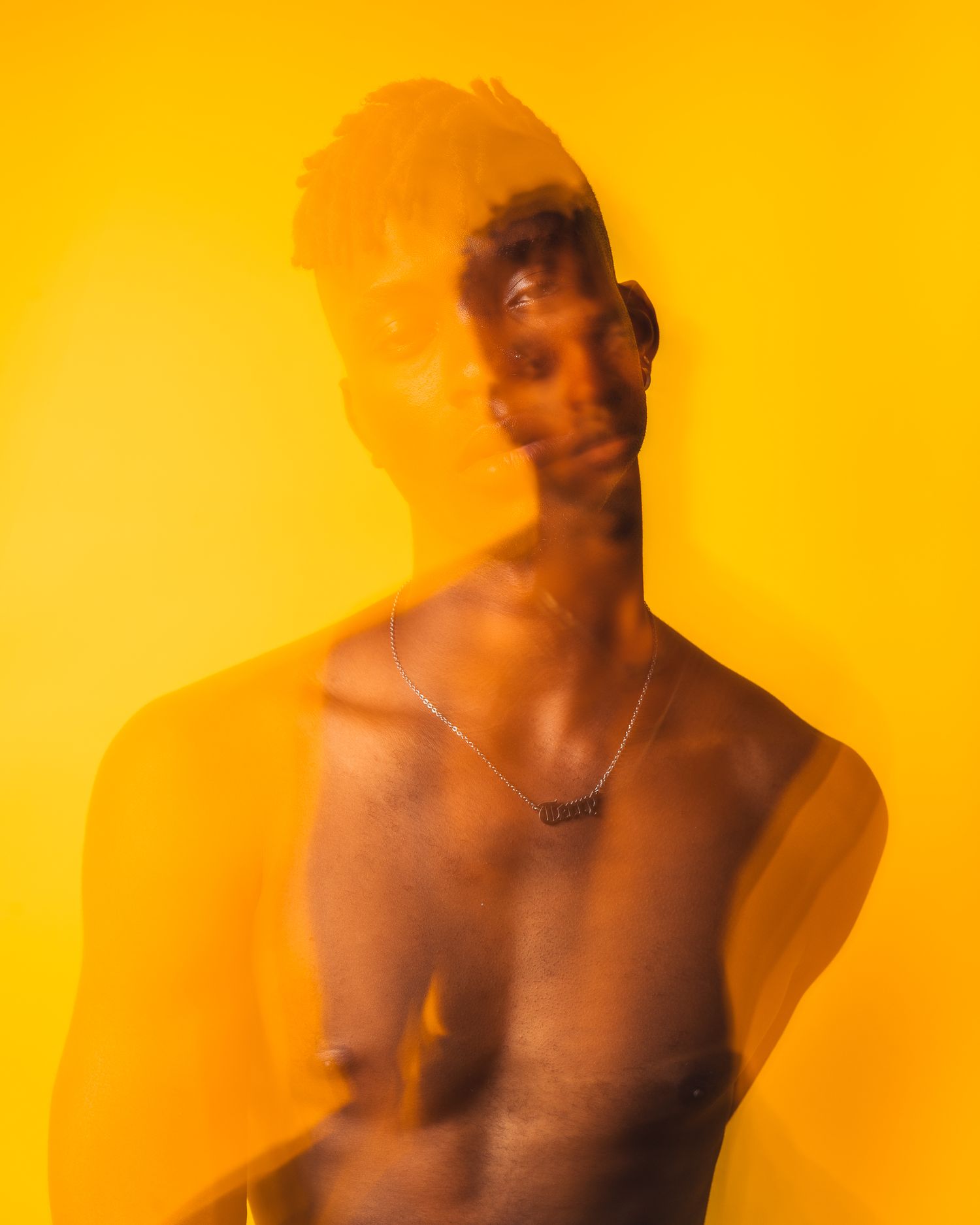 Artistic portrait with warm orange overlay effect against bright yellow background.