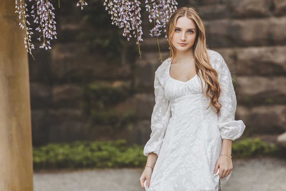 Elegant white dress portraits under hanging wisteria blossoms.