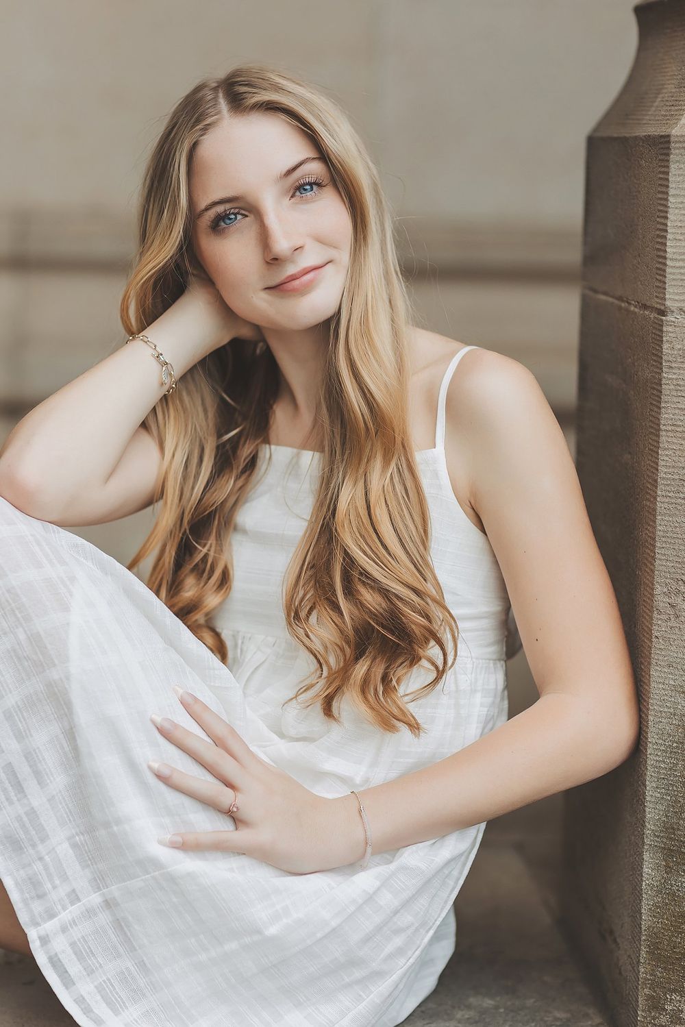 Elegant portrait of woman in flowing white dress with long wavy blonde hair.