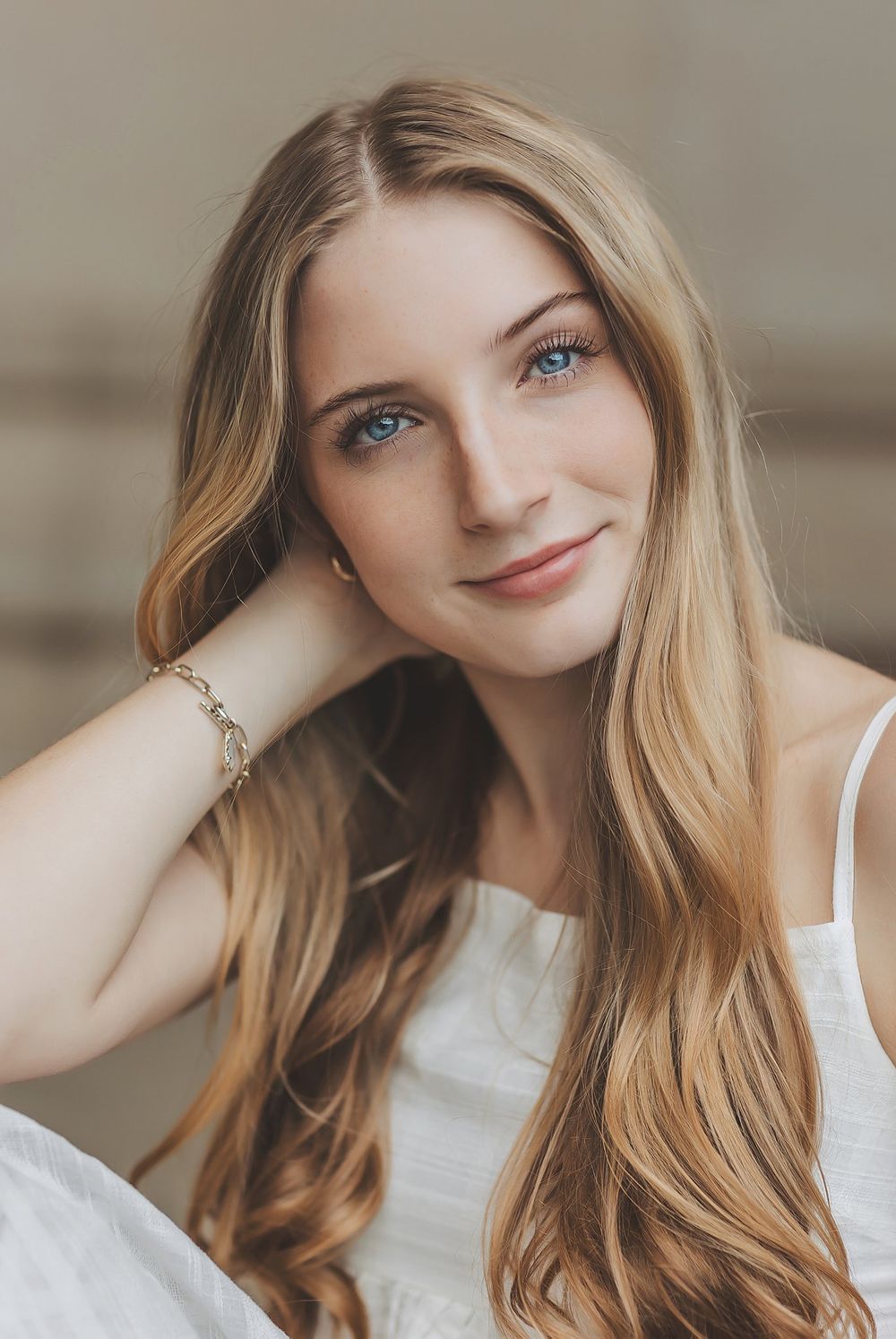 Soft portrait featuring serene smile and long wavy hair with natural makeup.