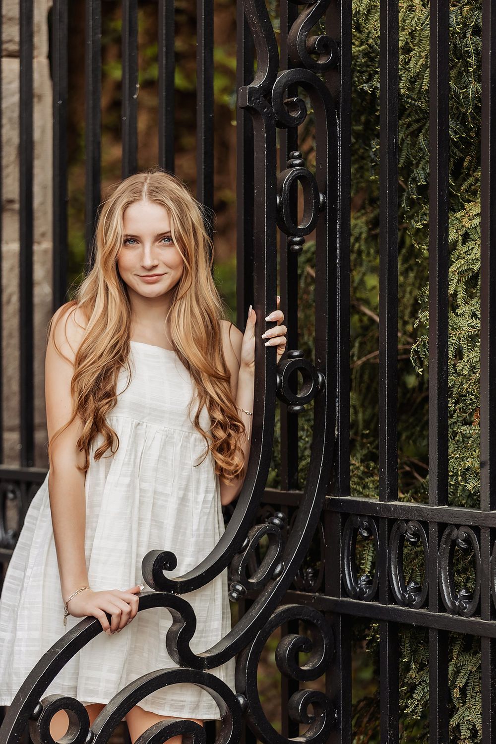 Artistic portrait featuring intricate black iron gate details and soft natural lighting.