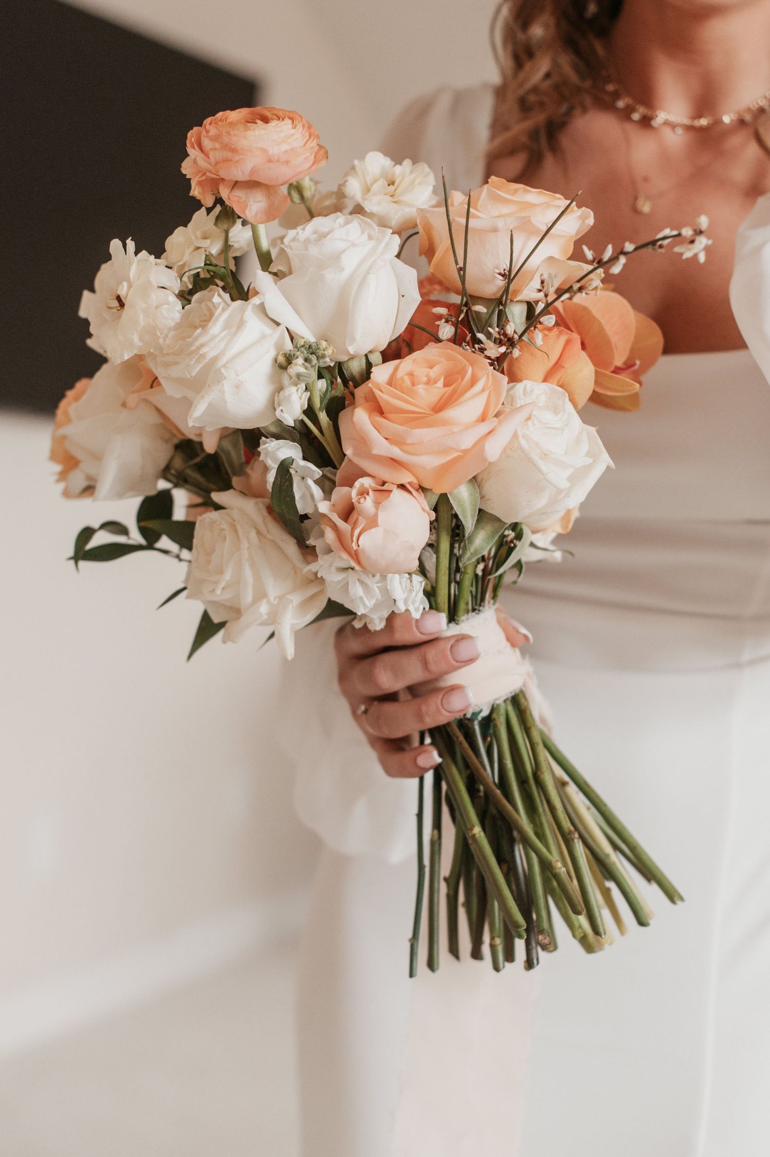 Elegant bridal bouquet featuring peach and white roses with delicate greenery.