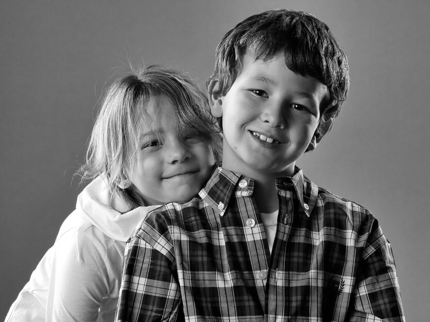 Black and white studio portrait series showing sibling interaction.