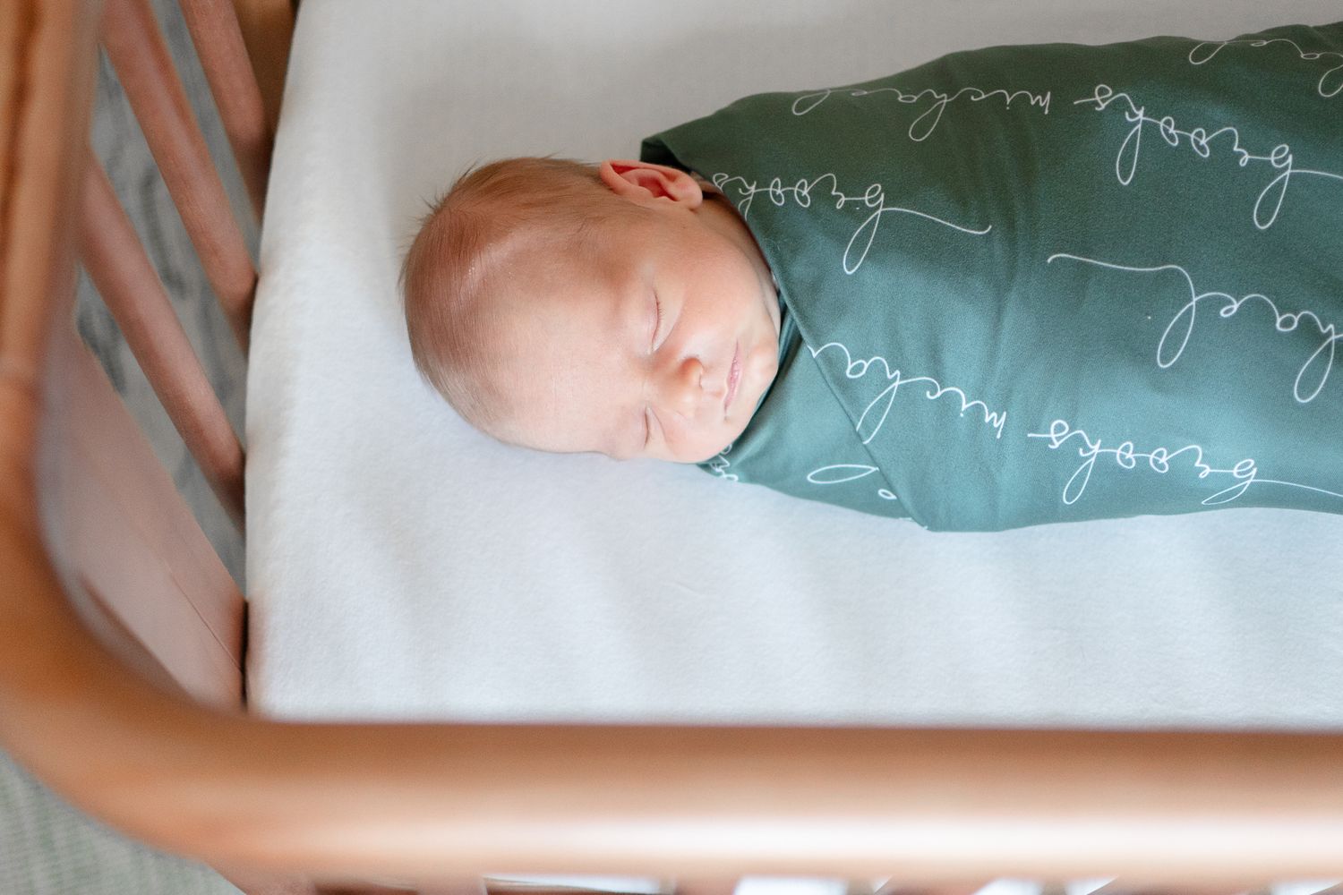 Newborn baby boy sleeps soundly in his crib during his at-home newborn photo shoot.