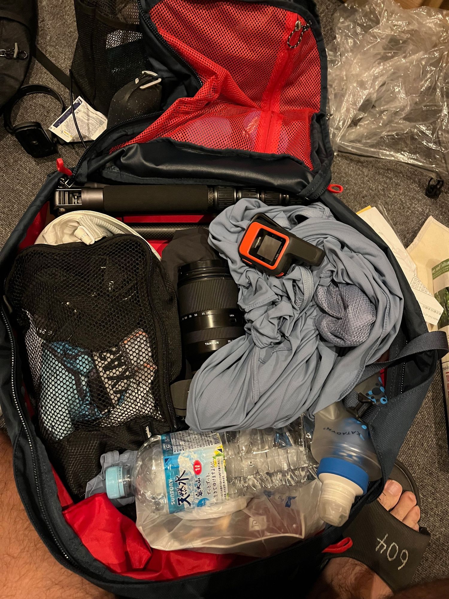 Open backpack showing packed camping gear, clothes, and water bottles.
