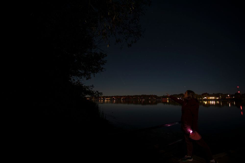 Alison of Lumenali Photography looks at Comet Tsuchinshan-ATLAS (C/2023 A3) in the distance at twilight, in Kingston, Ontario, Canada.