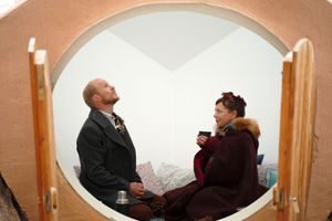Two people engage in conversation inside a circular archway.