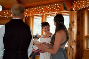 A wedding celebration in a log cabin venue with twinkle lights and natural wood beams.