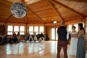 Wedding guests gathered in a rustic wooden reception hall decorated with string lights.
