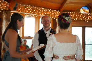 Wedding reception in a rustic wooden venue with twinkling string lights and large windows.