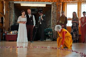 Wedding celebration in a rustic wooden hall with string lights and decorative posts.