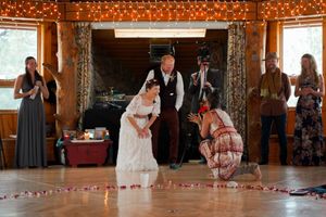 Wedding ceremony taking place in a wooden room decorated with string lights and floor petals.