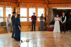 Large rustic reception hall with wooden beams and string lights creating a warm atmosphere.