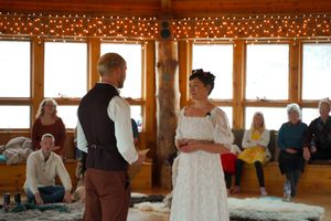 String lights decorate wooden beams as participants gather in a lodge for a group workshop.