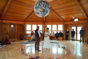 Panoramic view of a wooden event hall with vaulted ceilings and string light decorations.