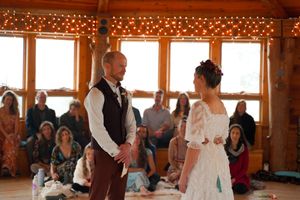 Indoor wedding ceremony in a sunlit wooden room decorated with string lights.