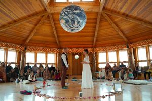 An octagonal wooden venue with a large Earth globe hanging from the ceiling during a wedding ceremony.