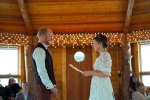 Wedding ceremony in a rustic wooden venue with string lights and natural lighting.