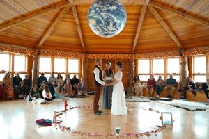 Wedding ceremony held in an octagonal wooden pavilion with natural lighting and circular floor arrangement.