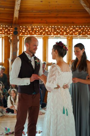 An intimate wedding ceremony in a wooden room decorated with string lights.