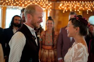 A tender moment captured between a couple during their wedding in a fairy-light decorated wooden venue.
