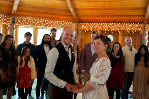 A wedding celebration in a rustic wooden venue with guests watching the happy couple.