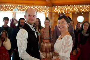 A joyful wedding ceremony moment inside a rustic venue with string lights.