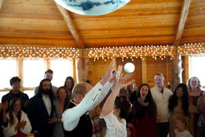 Celebratory moment with guests cheering and throwing confetti in a wooden-beamed reception hall.