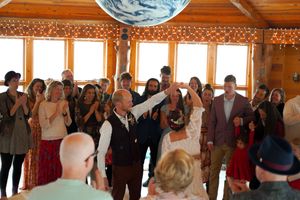 Celebration taking place in a rustic wooden pavilion with twinkling lights and gathered guests.