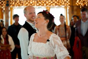 Couple dancing intimately beneath string lights at a rustic indoor celebration.