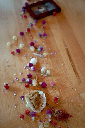 Scattered flower petals and decorative elements on wooden floor at wedding venue.
