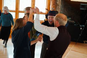 People dancing and celebrating in a bright room with large windows.