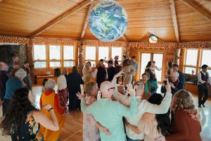 Wedding reception dance party in rustic venue with globe decoration and natural light.