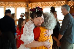 A warm embrace during a wedding celebration in a rustic venue with string lights.