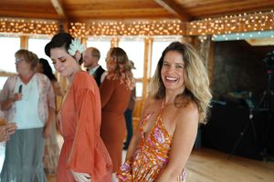 Wedding guests enjoying themselves at reception in rustic wooden pavilion with string lights.
