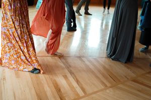 Flowing dresses and formal attire moving across a polished wooden dance floor.