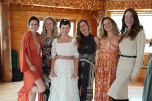 Group celebrating at rustic wedding reception venue with wooden walls and twinkling string lights overhead.