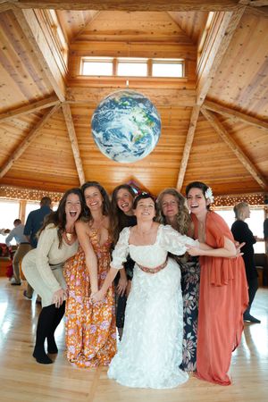 A group celebrating in a rustic wooden room with a large Earth globe pendant light overhead.
