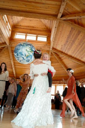 Dancing couples move across a wooden floor in a lodge decorated with twinkling lights and natural wood beams.