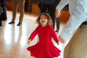 Wedding guests dancing and twirling in formal attire on a polished wooden dance floor.