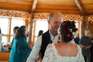 Couples dancing in an elegant rustic venue with wood beam ceiling and string light decorations.