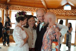 Wedding guests dance and celebrate together in a rustic wooden venue decorated with twinkling lights.