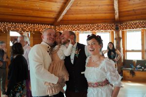 Couples dancing in a rustic wooden reception hall with string lights creating a warm, romantic atmosphere.